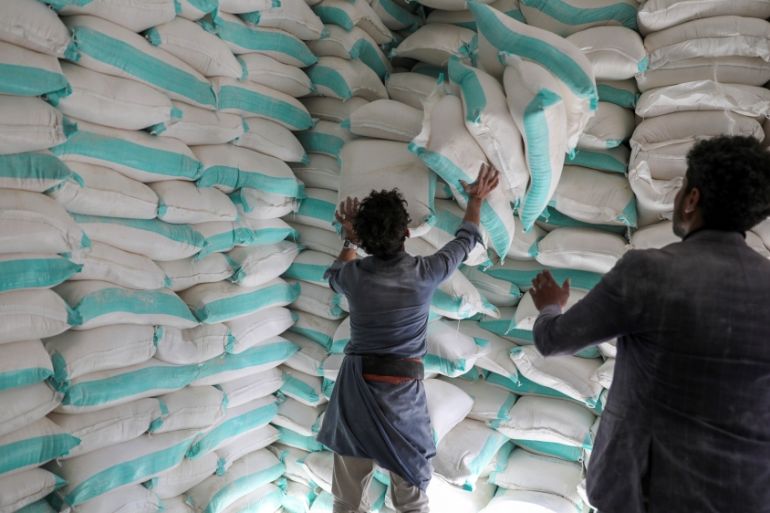 Workers handle sacks of wheat flour at a World Food Programme food aid distribution center in Sanaa