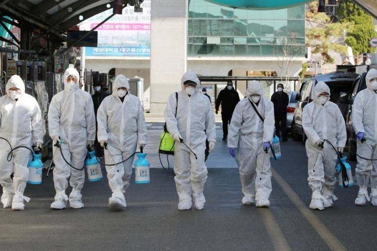 Market workers wearing protective gear spray disinfectant at a market in the southeastern city of Daegu on February 23, 2020 as a preventive measure after the COVID-19 coronavirus outbreak. South Kore