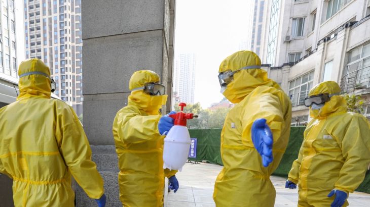 Funeral parlour staff members in protective suits help a colleague with disinfection after they transferred a body at a hospital, following the outbreak of a new coronavirus in Wuhan, Hubei province,
