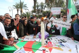Demonstrators gather around a candle to mark the first anniversary of protests in Algiers