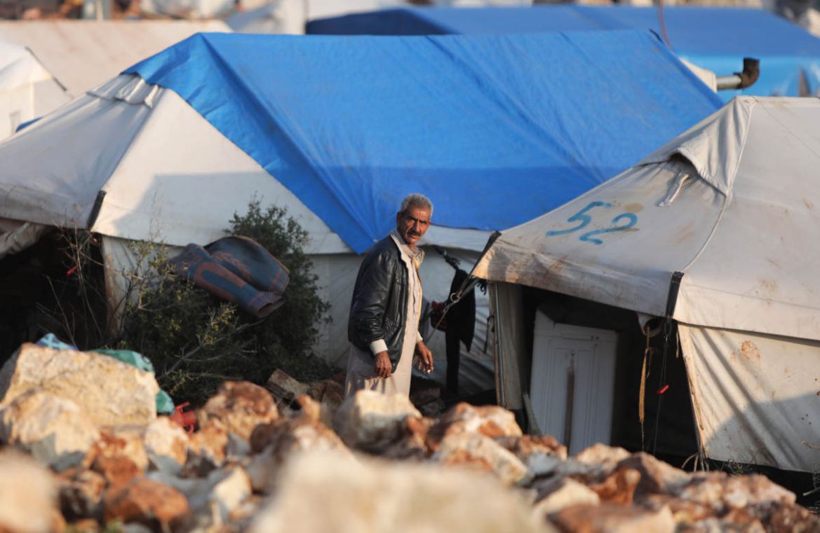A Syrian man stands at a makeshift camp for displaced people who fled pro-regime forces attacks in the Idlib and Aleppo provinces, on February 18, 2020 north of the city of Idlib, near the Turkish bor