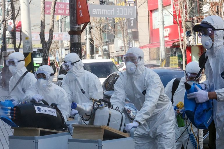 Workers wearing protective gears spray disinfectant as a precaution against the coronavirus at a shopping street in Seoul, South Korea, Thursday, Feb. 27, 2020. The new illness persists in the worst-h