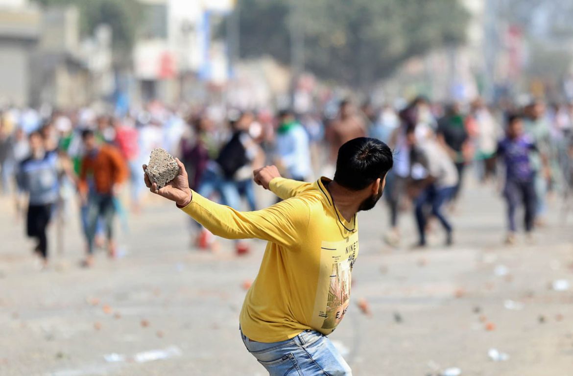 A man supporting a new citizenship law throws a stone at those who are opposing the law, during a clash in New Delhi, India, February 24, 2020. REUTERS/Danish Siddiqui