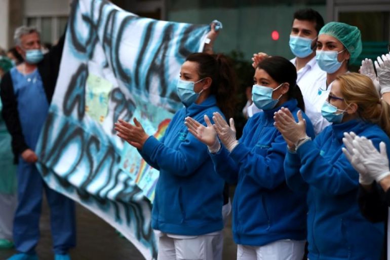 Medical staff in Madrid react as neighbours applaud from their balconies. Health workers urrently account for 14 percent of all coronavirus cases in Spain [Sergio Perez/Reuters]