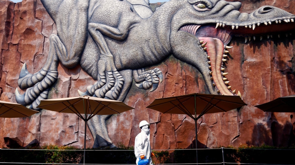 A worker wearing protective suit passing by near a wall where is depicted a dinosaur at Dufan, which is closed amid the coronavirus disease (COVID-19) outbreak spreading in Jakarta