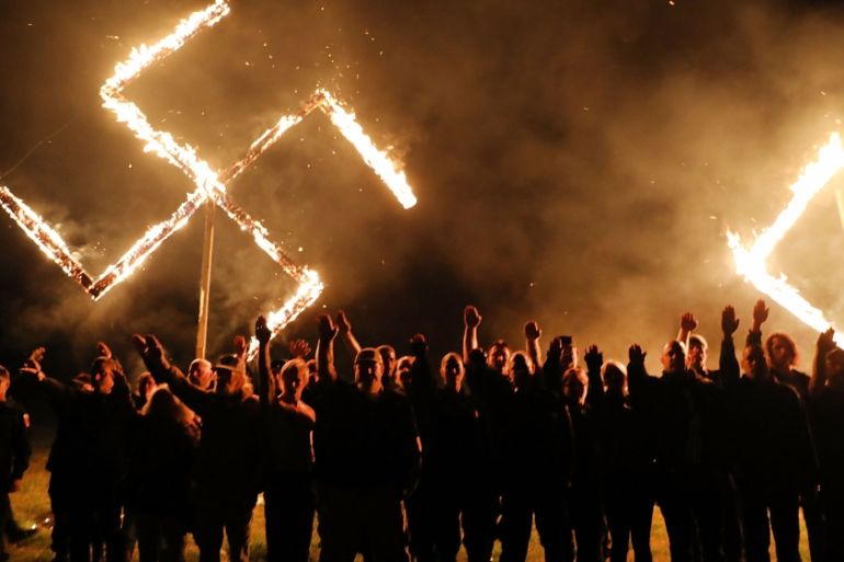 Members of the National Socialist Movement, one of the largest neo-Nazi groups in the US, hold a swastika burning after a rally on April 21, 2018 in Draketown, Georgia. Community members had opposed t