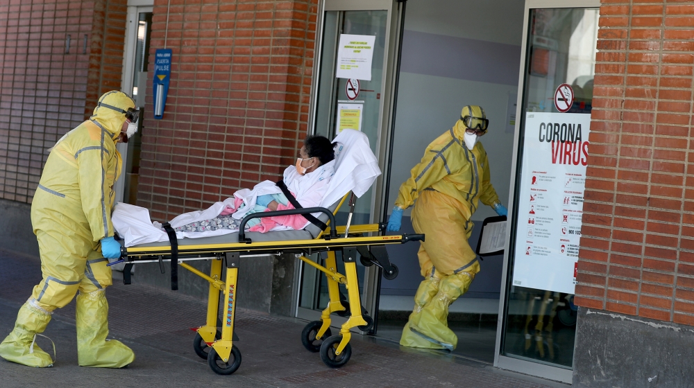 Ambulance workers in full protective gear arrive with a patient at the Severo Ochoa Hospital during the coronavirus disease (COVID-19) outbreak in Leganes, Spain, March 26, 2020. REUTERS/Susana Vera