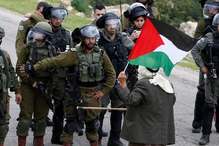 A demonstrator holding a Palestinian flag stands in front of Israeli forces during a protest against Israeli settlements and the U.S. President Donald Trump''s Middle East peace plan, in Jordan Valley