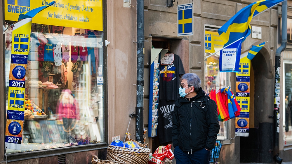 A toursit wears a protective face mask as he visits the old town in Stockholm on March 13, 2020. (Photo by Jonathan NACKSTRAND / AFP)
