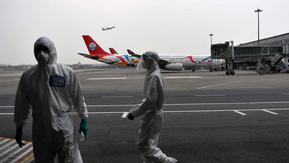 Customs officers in protective suits are seen near a Sichuan Airlines aircraft on the tarmac of Chengdu Shuangliu International Airport
