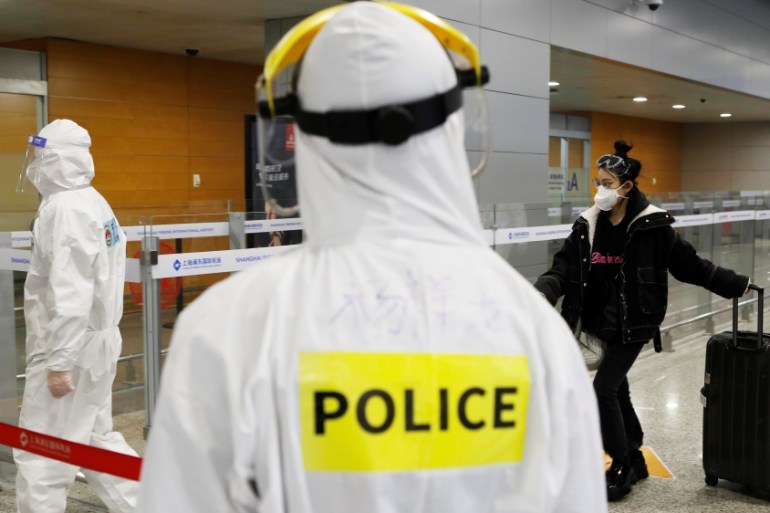 Police officer in a protective suit keeps watch on inbound travellers at Shanghai Pudong International Airport following a global outbreak of coronavirus disease