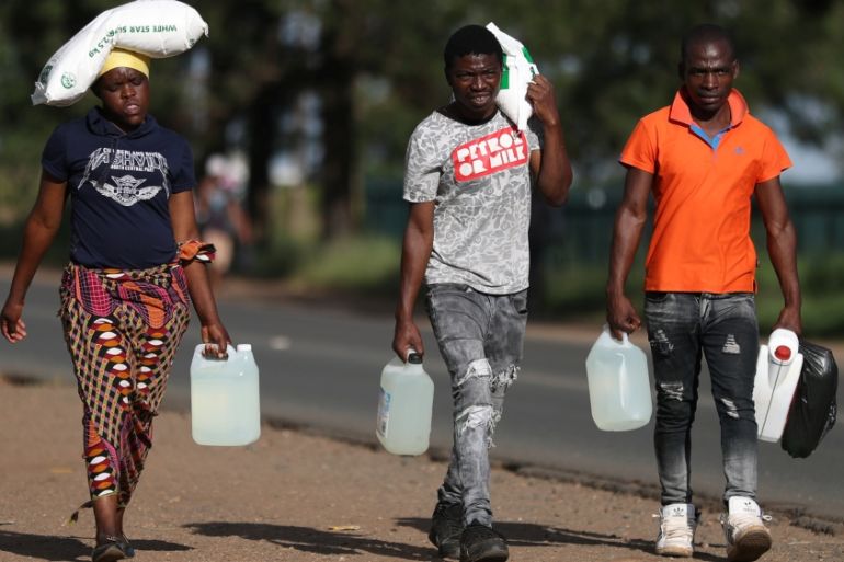 People carry bags of maize and paraffin as they return from a store ahead of a nationwide lockdown, in Johannesburg