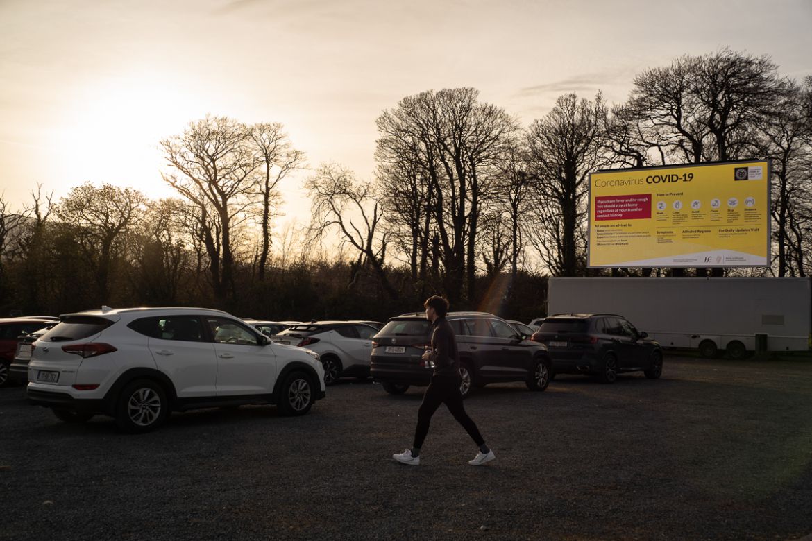 Dozens of cars attending the screening are instructed to carefully line up at 1.5 meters apart, as messages displaying guidelines for social distancing measures aimed at minimising the spread of Covid