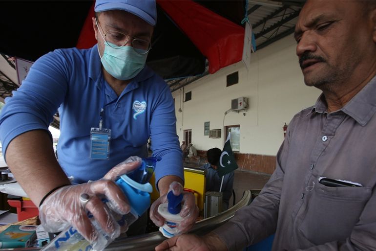 A Pakistani volunteer helps a passenger arriving at a railway station to wash hands as a measure to help prevent the spread of the coronavirus, in Peshawar, Pakistan, Tuesday, March 17, 2020. For most
