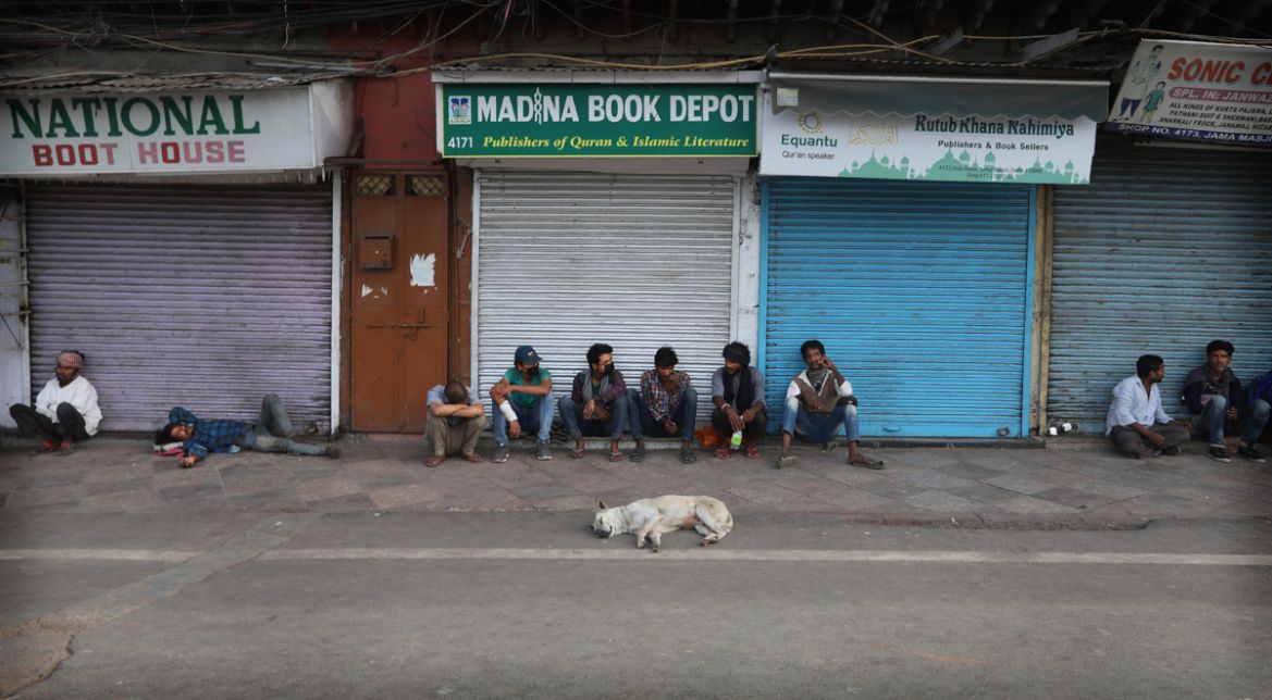 Homeless people sit outside closed shops and a stray dog sleeps during a lockdown to control the new virus spread, in New Delhi, India, Wednesday, March 25, 2020. The world''s largest democracy went un