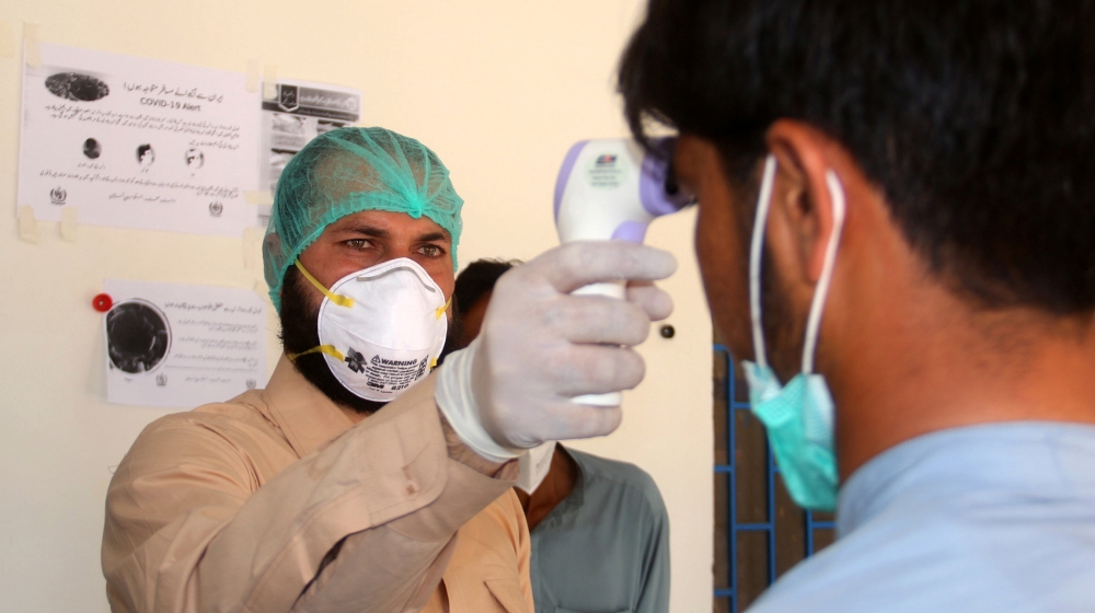 A health worker takes the temperature of a man who returned from Iran and is under medical observation, after Pakistan sealed its border with Iran as a preventive measure following the coronavirus out