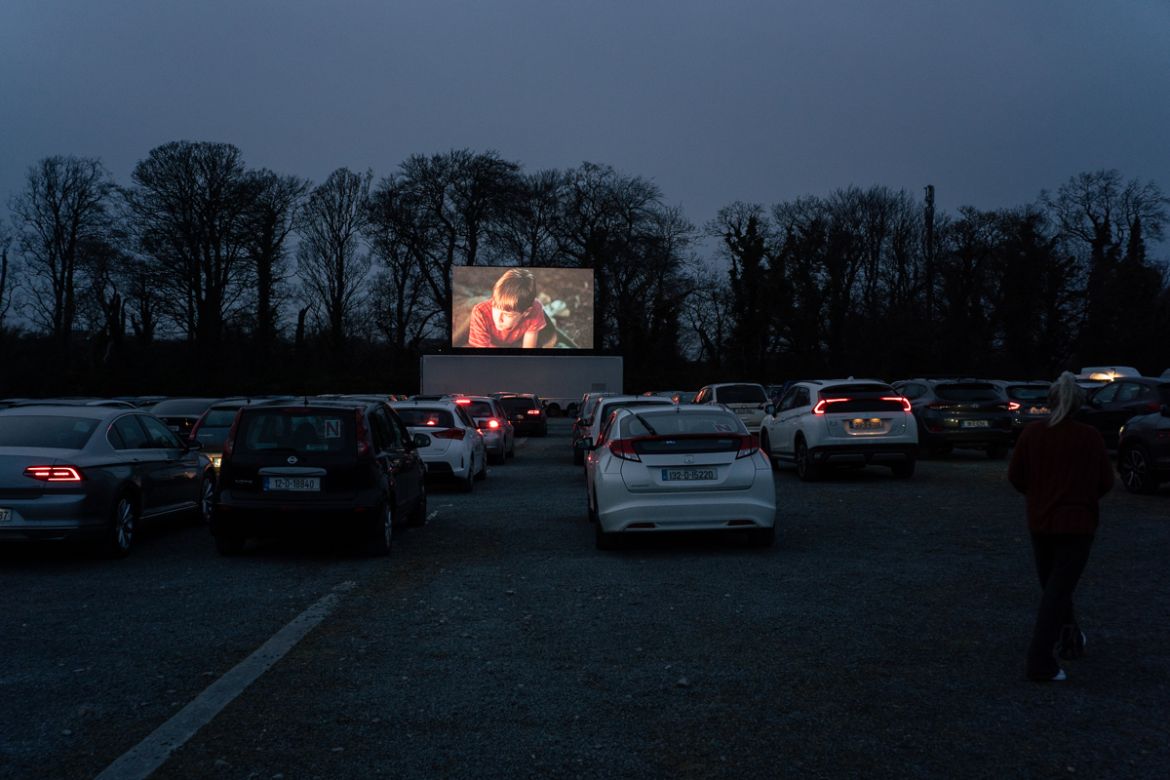 Dozens of cars attending the screening are instructed to carefully line up at 1.5 meters apart, as messages displaying guidelines for social distancing measures aimed at minimising the spread of Covi