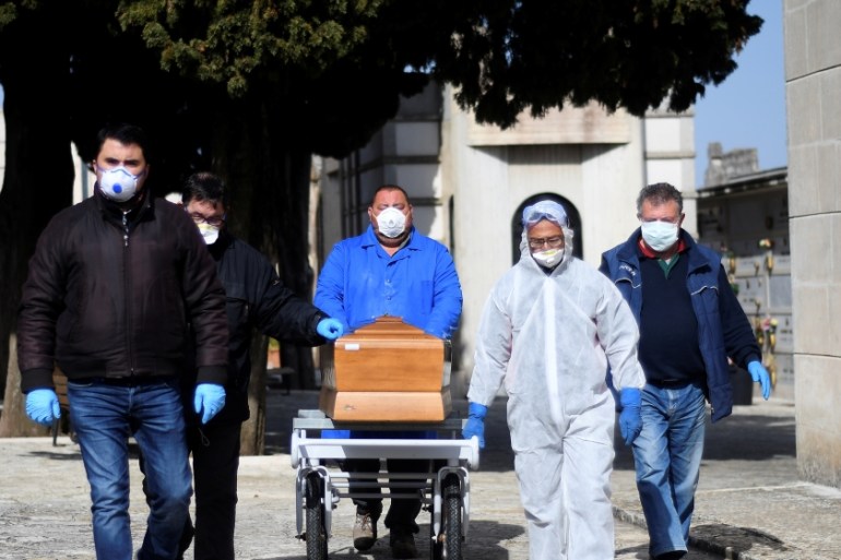 Funeral service workers transport a coffin of a victim of coronavirus disease (COVID-19) during a ceremony in the southern town of Cisternino, Italy March 30, 2020. REUTERS/Alessandro Garofalo