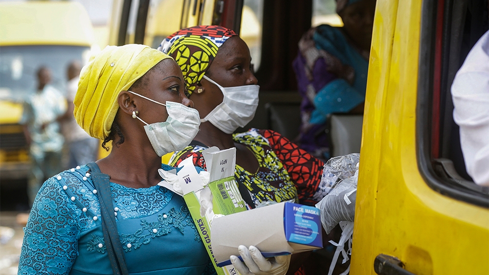 Women sell face masks and gloves, to prevent the spread of the new coronavirus, to passengers at a public minibus station in Lagos, Nigeria Friday, March 27, 2020. The new coronavirus causes mild or m