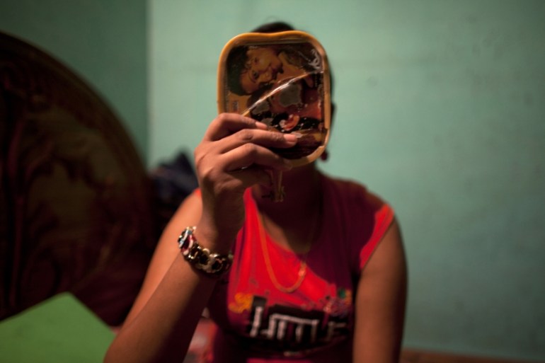 Twelve-year-old prostitute Mukti applies makeup before serving a customer inside her small room at a brothel in Faridpur, located in central Bangladesh