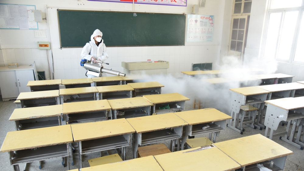Worker in protective suit sprays disinfectant inside a classroom of a primary school, as students’ return has been delayed, in Donghai county of Lianyungang, Jiangsu