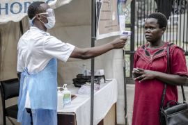 Health personnel measure the temperature of a visitor at the entrance of the Coptic Hospital in Nairobi, Kenya on March 18, 2020. The Government of Kenya confirmed new positive cases of COVID-19 coron