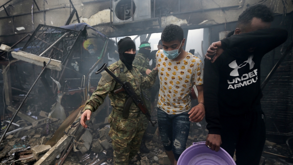 A Palestinian Hamas militant controls the scene where a fire broke out in a market in the central Gaza Strip