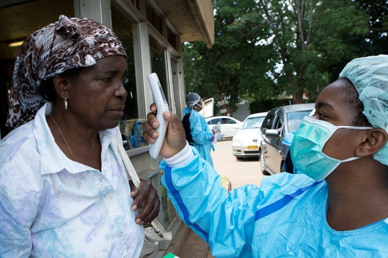 A woman is screened by a Health worker before visiting a relative at a public hospital in Harare, Zimbabwe ,Saturday, March, 21, 2020 . Zimbabwe announced its first case of coronavirus,in one of