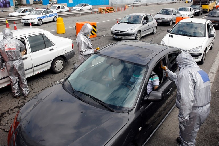epaselect epa08323825 Members of Iranian red crescent test people with possible coronavirus Covid-19 symptoms, as police blocked Tehran to Alborz highway to check every car following ordered by Irania