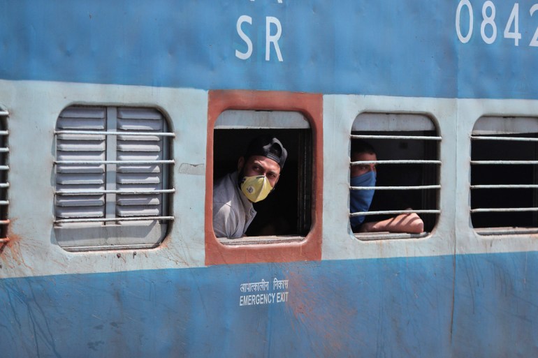 Passengers wearing masks look out from a train in Jammu, India.