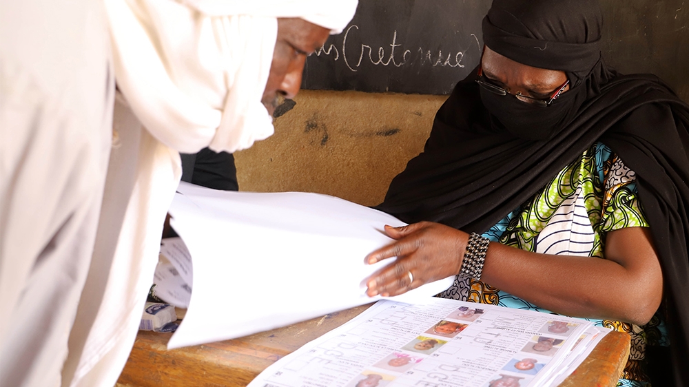 A voter (L) and an electoral official (R) checks the voters roll at a polling station during the parliamentary elections in Gao, Mali, on March 29, 2020. - Malians headed to the polls on March 29, 202