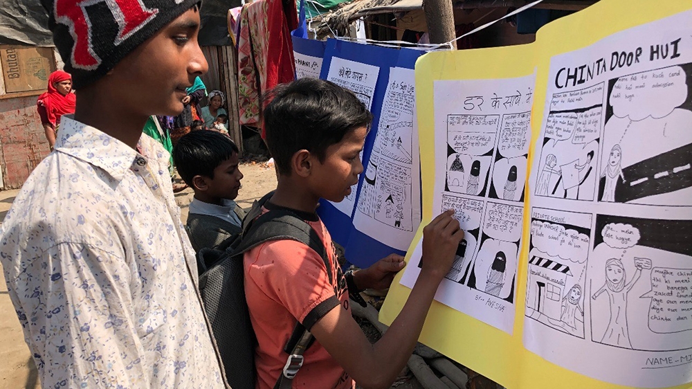 Rabi Alam, 14 pictured left, Rohingya participants reading storyboards of their comics [Tasnim Nazeer/Al Jazeera]