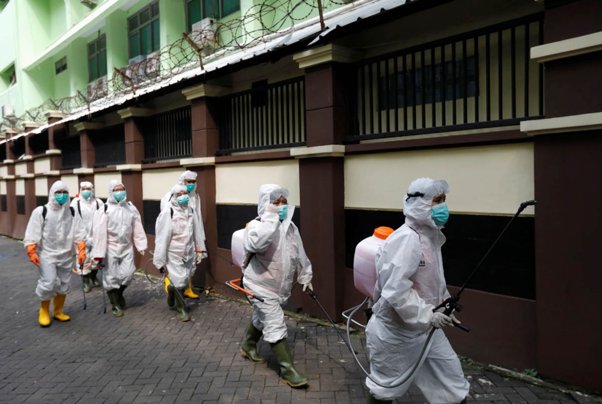 Volunteers from Indonesia''s Red Cross, wearing protective suits, walk while carrying disinfectant sprayers at a school complex, closed amid the spread of coronavirus (COVID-19) in Jakarta, Indonesia,