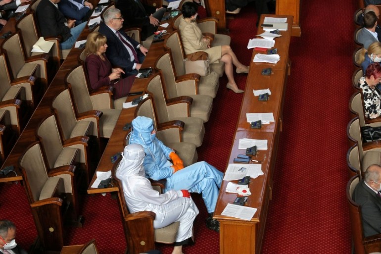 Leader of Bulgarian party Volya, Mareshki, and a deputy from his party wear protective suits during debates in the parliament in Sofia