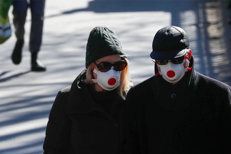 Two people wearing masks walk in Regents Park in London, Monday, March 23, 2020. The British government is encouraging people to practice social distancing to help prohibit the spread of Coronavirus,