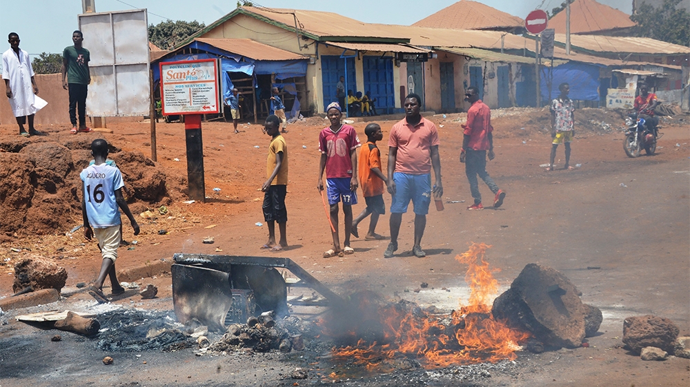 Protesters stand next to burning tyres during a protest in Conakry on March 21, 2020, on the eve of a constitutional referendum in the country. - Guinean President Alpha CondE` assured on March 21, 20