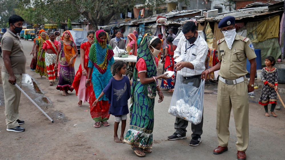 Slum dwellers receive free food packets during a 21-day nationwide lockdown to limit the spread of the coronavirus disease (COVID-19), in Ahmedabad