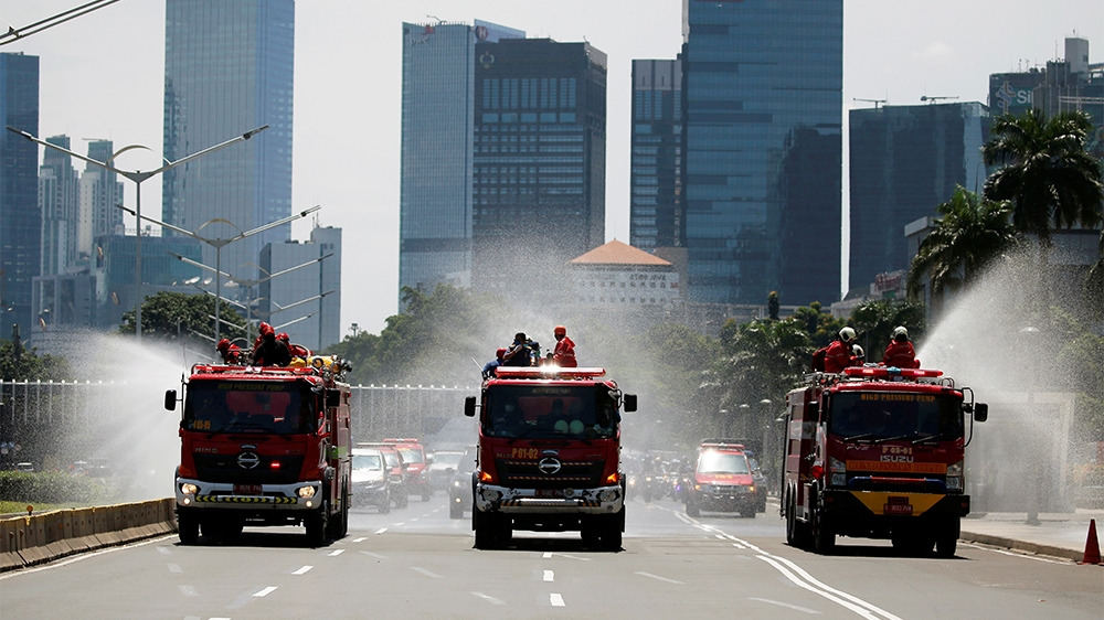 Firefighters spray disinfectant using high pressure pump trucks to prevent the spread of coronavirus disease (COVID-19), on the main road in Jakarta, Indonesia, March 31, 2020. REUTERS/Willy Kurniawan