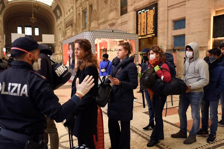 A police officer talks to people at Milan''s main train station, following a government decree that has shut down large areas in the north of the country, to stem coronavirus contagion