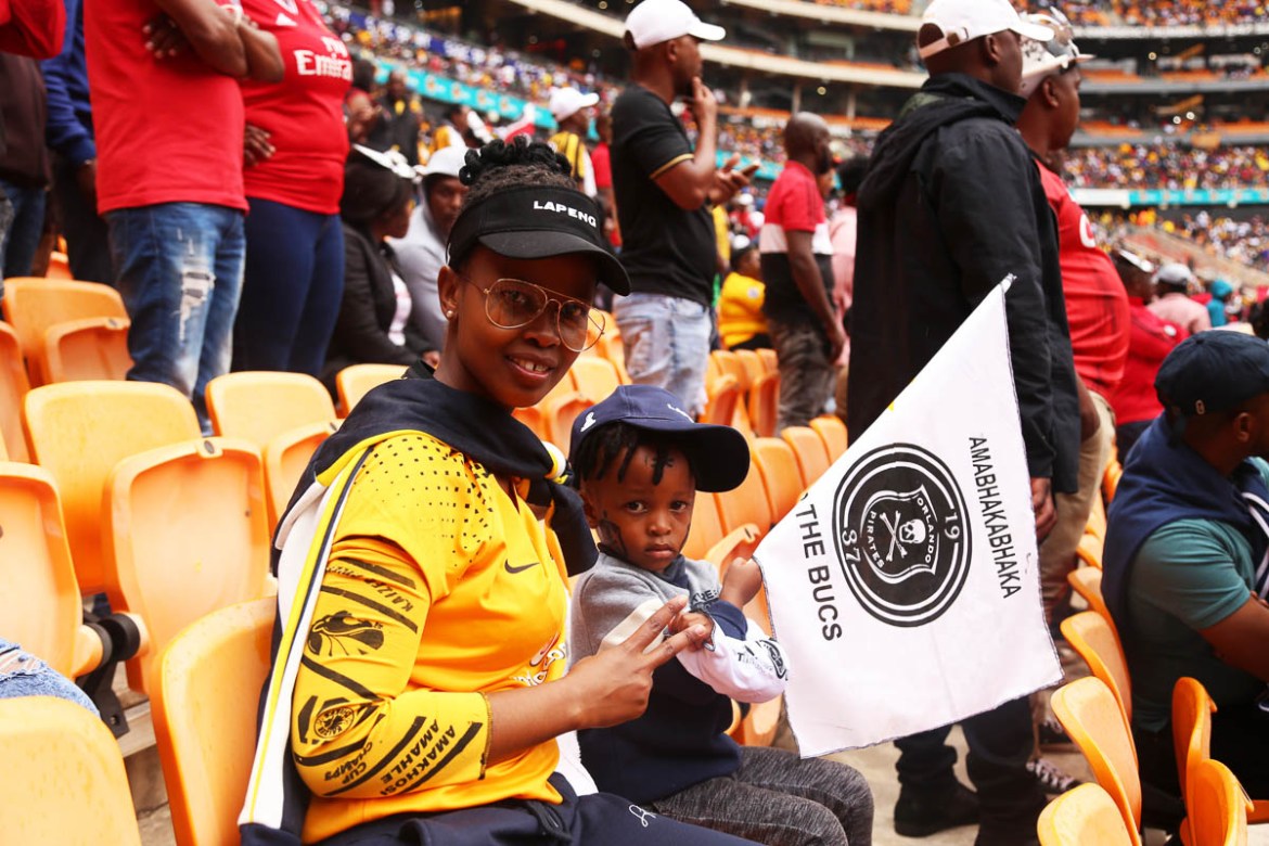 Busisiwe and her 4 year old son Awethu at FNB stadium. She supports Kaizer chiefs but her son and husband support Orlando Pirates. Sje says she does not mind and that during the game although seated