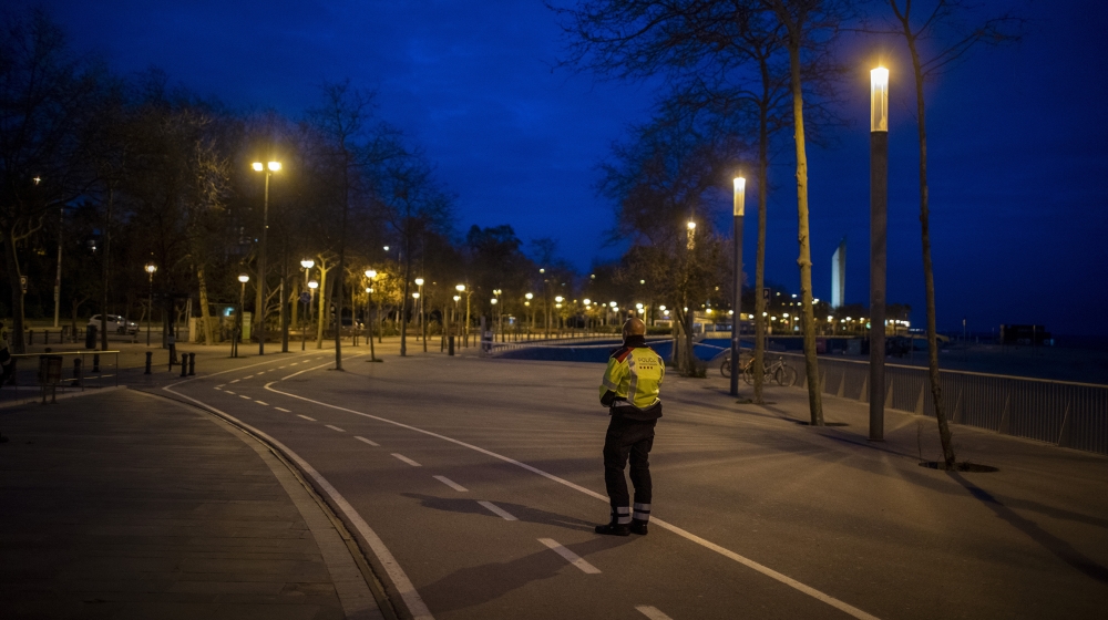 A Catalan police officer stands guard in an empty promenade in Barcelona, Spain, Saturday, March 28, 2020. Spanish Prime Minister Pedro SÃ¡nchez has announced that his government will order a two-week