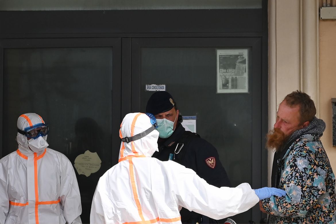 Members of the medical staff wearing a proective uniform, rescue an homeless man in Ostia, in the outskirts of Rome, on March 21, 2020 during the country''s lockdown aimed at stopping the spread of the