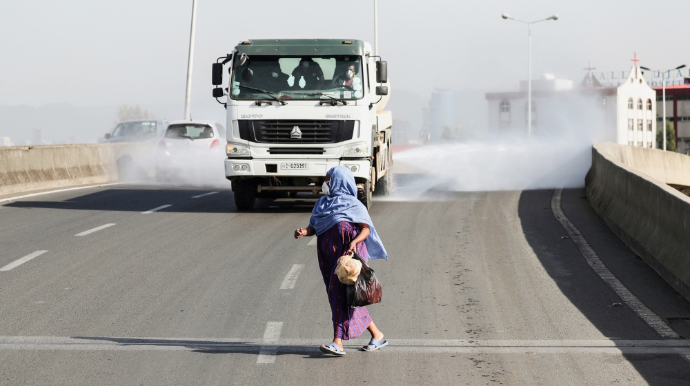 A woman wearing a face mask, runs in front of a truck spraying disinfectant on the street as part of measures to prevent the potential spread of coronavirus (COVID-19), in Addis Ababa, Ethiopia March 
