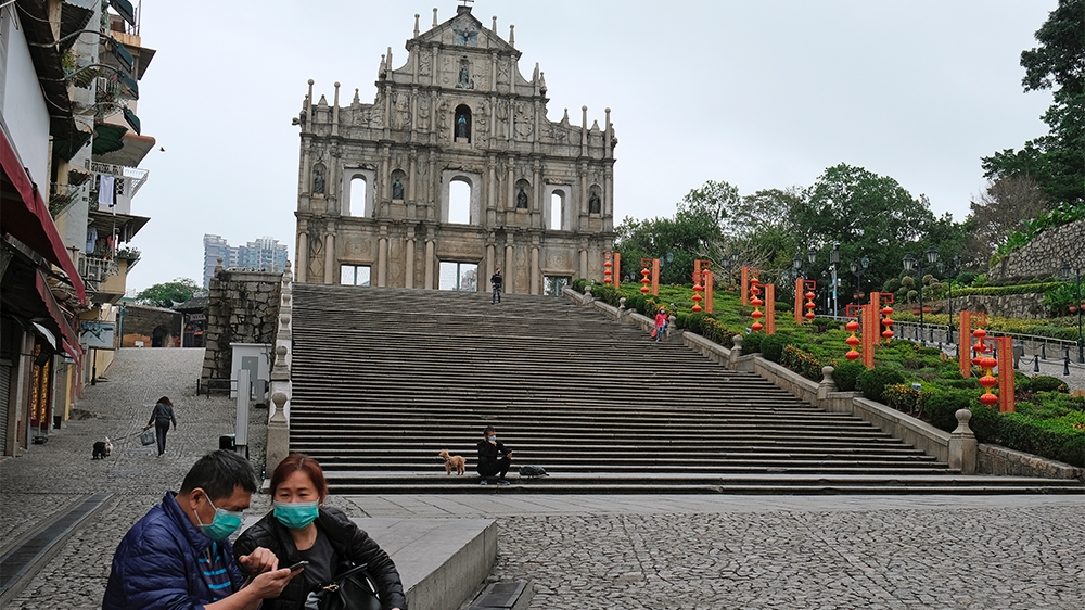 People wear masks as they walk in front of the Ruins of St. Paul’s, following the coronavirus outbreak in Macau, China February 5, 2020. REUTERS/Tyrone Siu