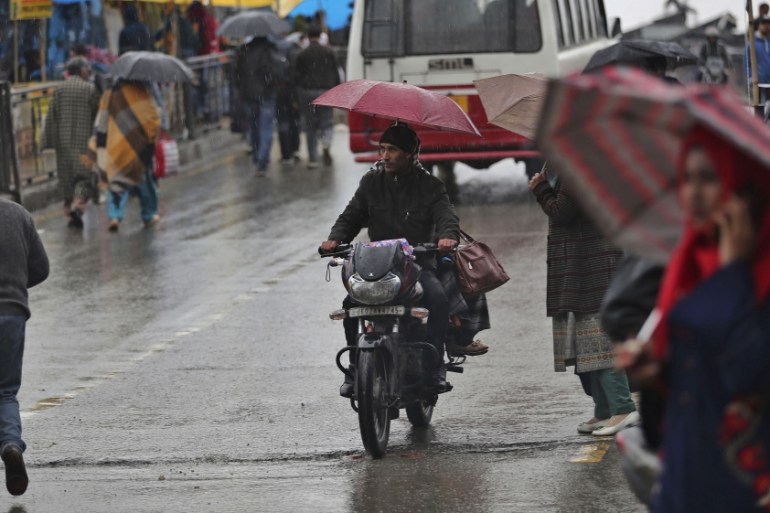 Kashmiri hold umbrella’s as it rain in Srinagar Indian controlled Kashmir, Thursday, March 12, 2020. (AP Photo/Mukhtar Khan)