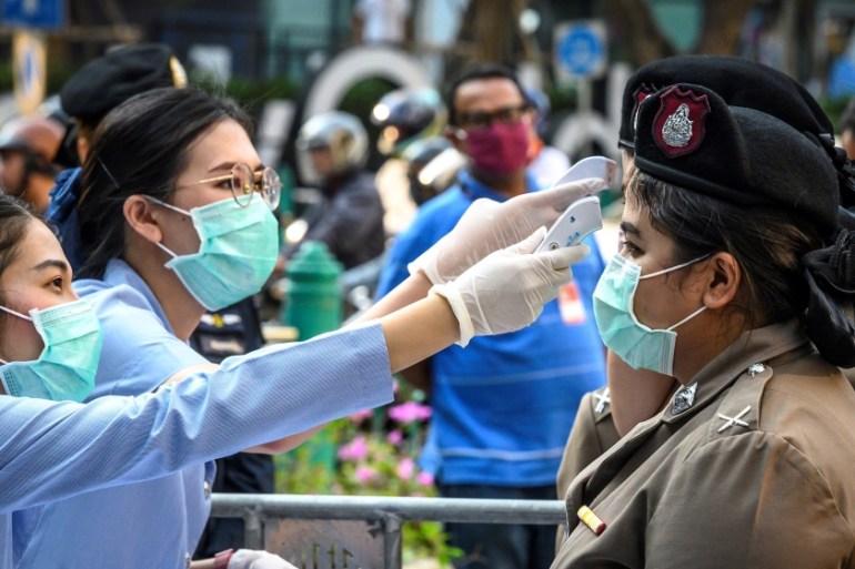 Health officials, wearing face masks amid fears over the spread of the COVID-19 novel coronavirus, check the body temperature of policewomen before an anti-government rally in Bangkok on March 1, 2020
