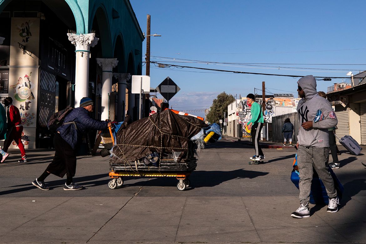 epa08305457 A homeless man pushes a cart in Venice Beach amid the coronavirus pandemic, in Los Angeles, California, USA, 18 March 2020. Homeless people are particularly at risk of contracting the viru