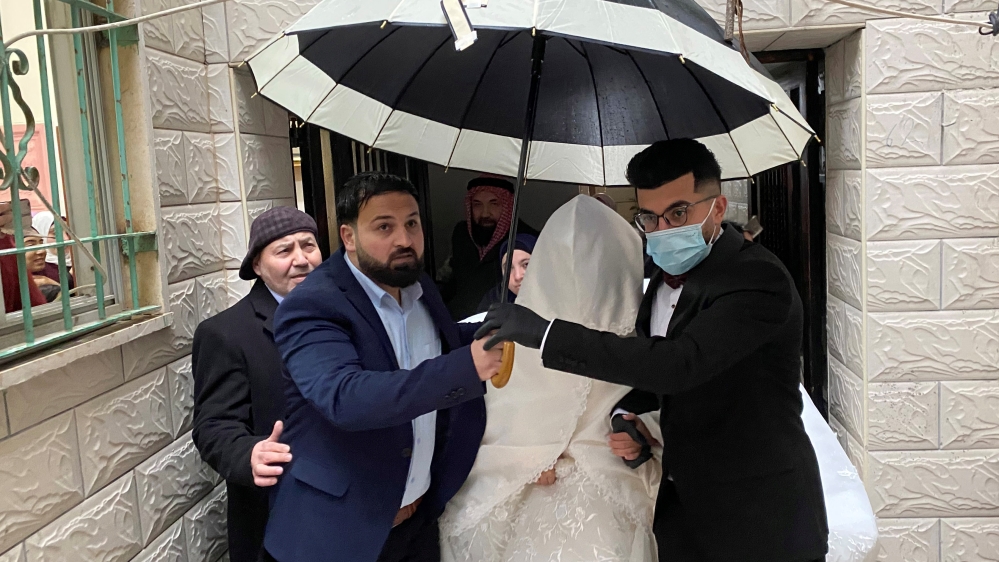 A Palestinian groom, wearing a mask as a preventive measure against the coronavirus disease, leaves with his bride her family house, on their wedding day in Beit Jala in the Israeli-occupied West Bank