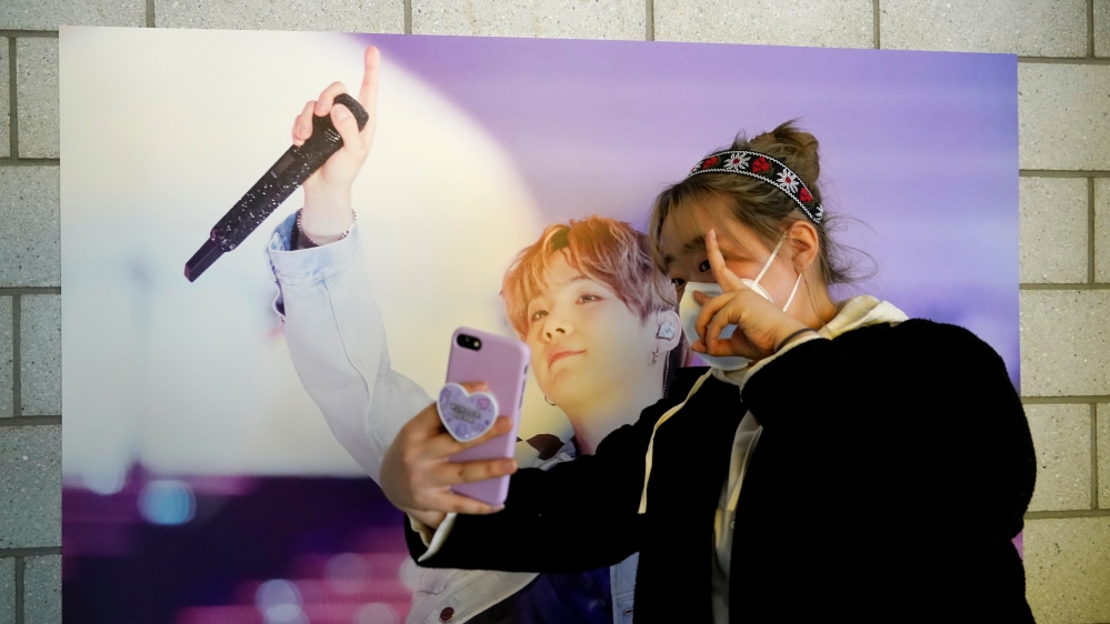 Im Yu-mi, fan of K-pop boy band BTS, takes a selfie at a cafe decorated with photos and merchandise of them, in Seoul, South Korea