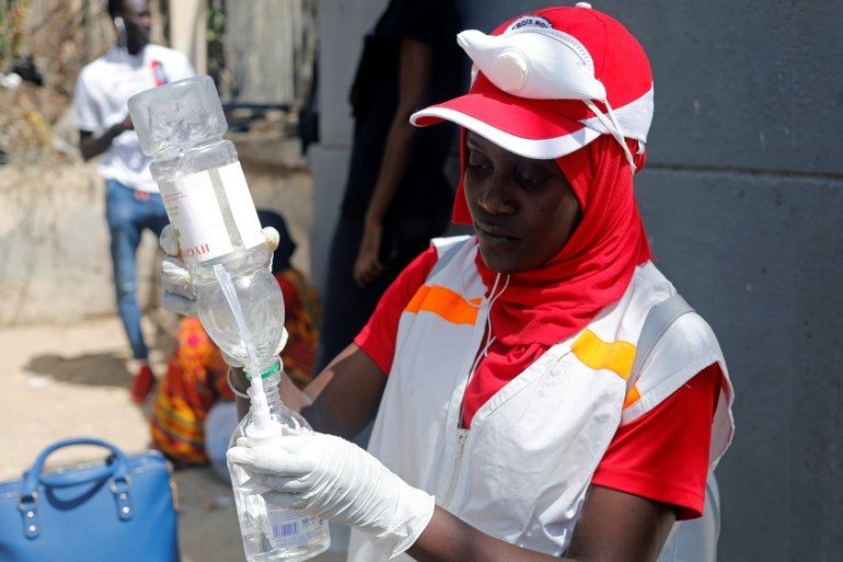 A Red Cross worker fills a bottle with a sanitising hand gel at the entrance of Cheikh Anta Diop University in Dakar